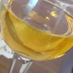 Złocisty płyn w kieliszku, być może aromatyczne wino mandarynkowe, odbija światło.