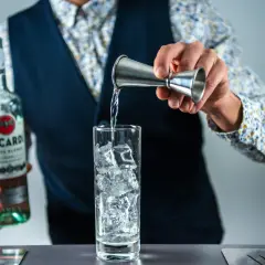 Barman nalewa Bacardi do szklanki z lodem, przygotowując klasycznego Cuba Libre.