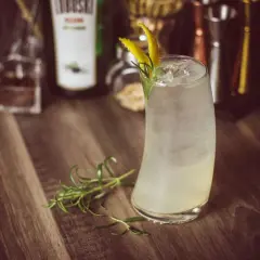 Orzeźwiający drink z lodem i cytrynową skórką, przypominający bombay sunset. Gałązka rozmarynu dodaje aromatu.